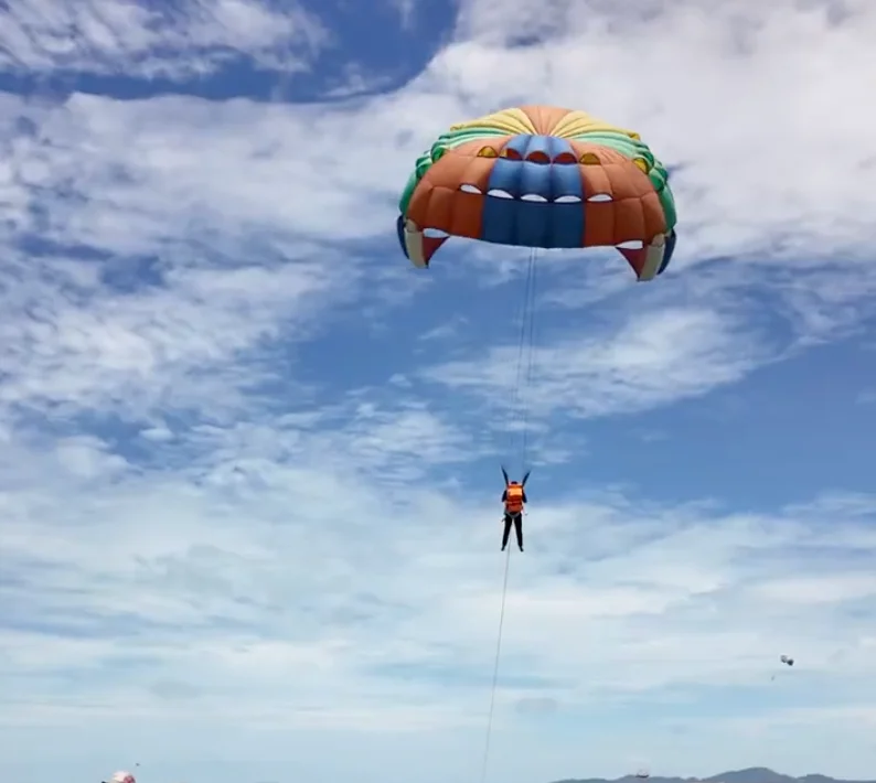 A tourist flying high over the Gulf of Thailand while parasailing during a Coral Island day trip.